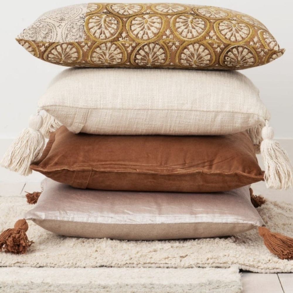 Stapel kussens in oker, crème en terracotta met kwastjes