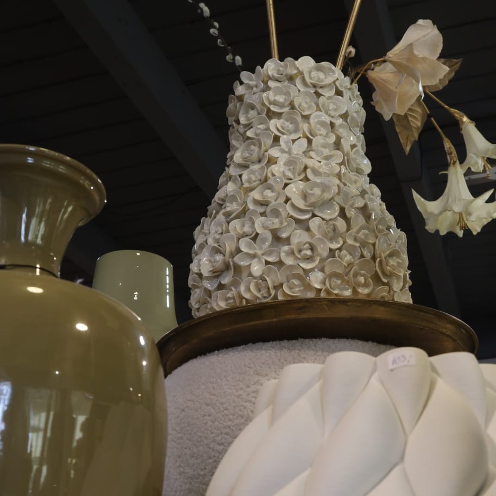 Witte vaas met porseleinen bloemen tussen keramiek in de winkel